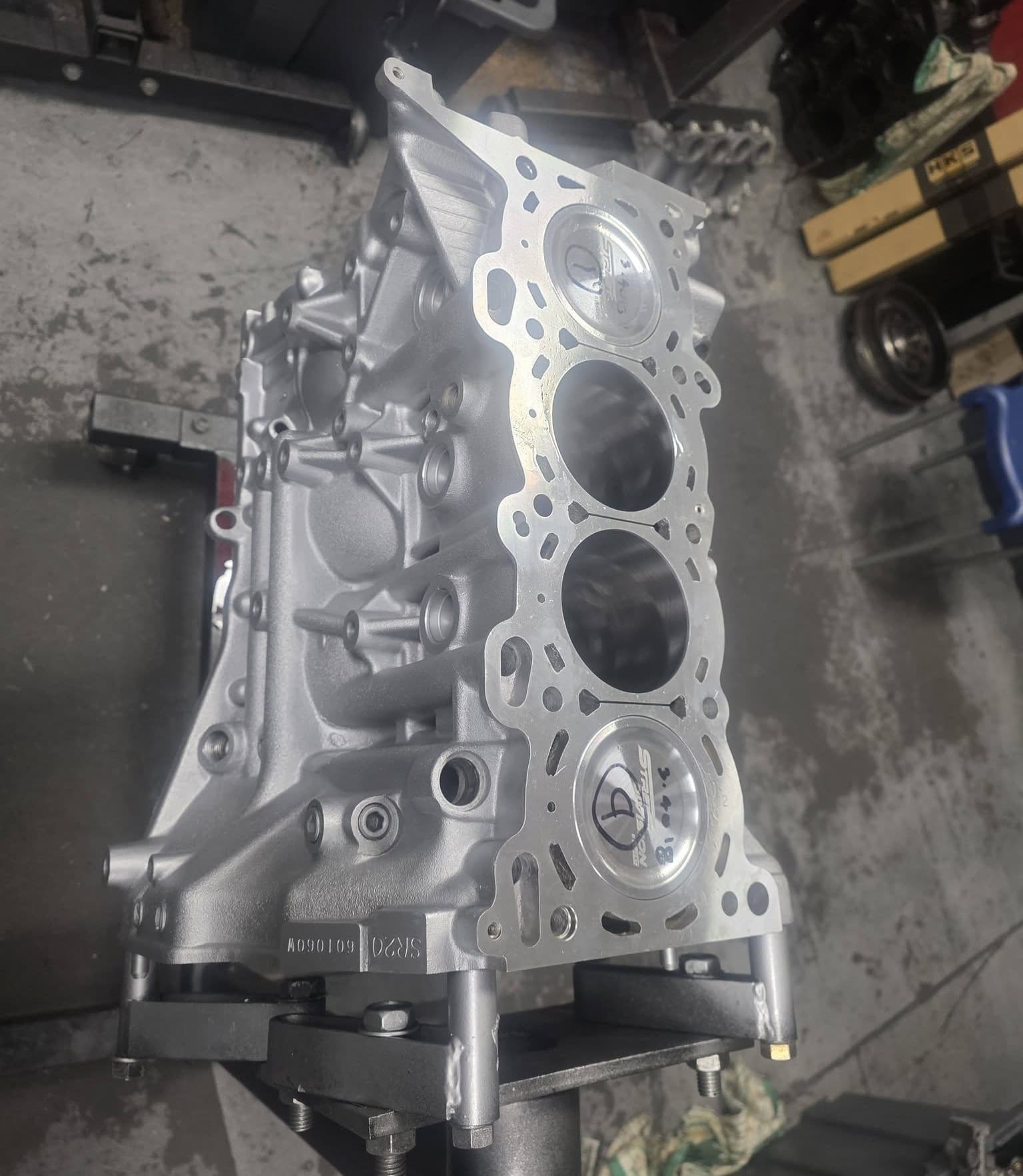 An RB26 short block on the bench with fresh pistons in the bores and head studs fitted