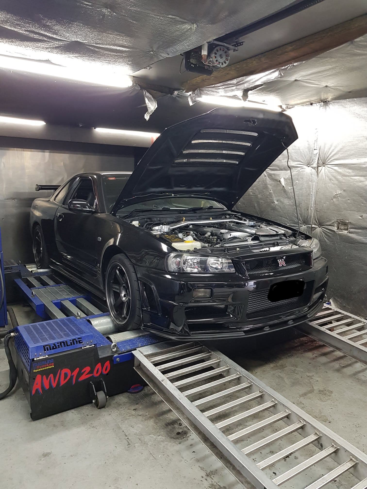 Nissan Skyline R32 GT-Rs in the MRC Dyno workshop, one raised on the hoist